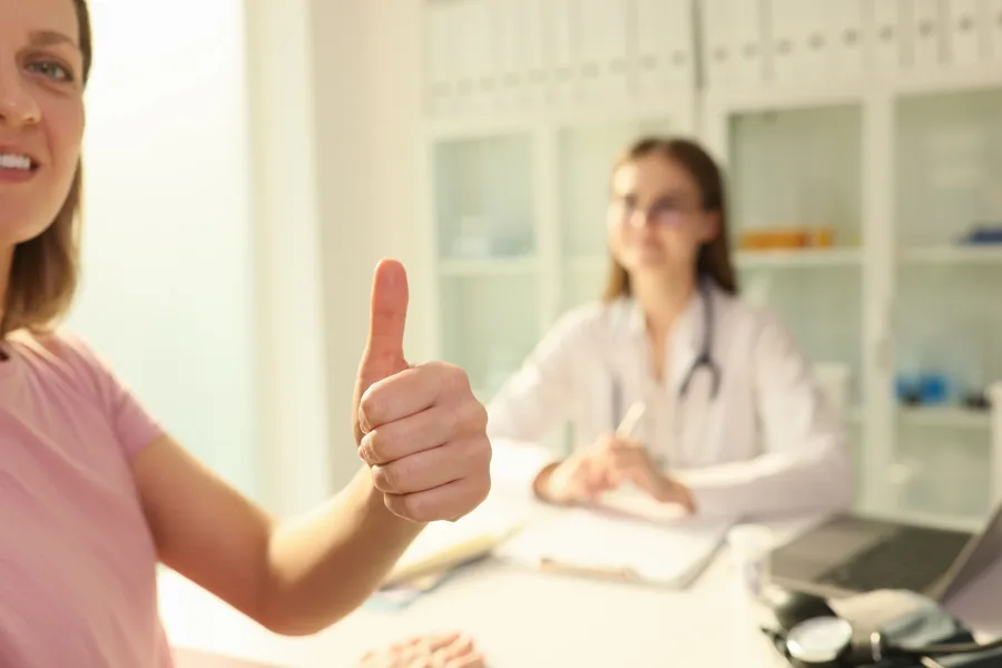 Happy patient giving a thumbs up after her consultation